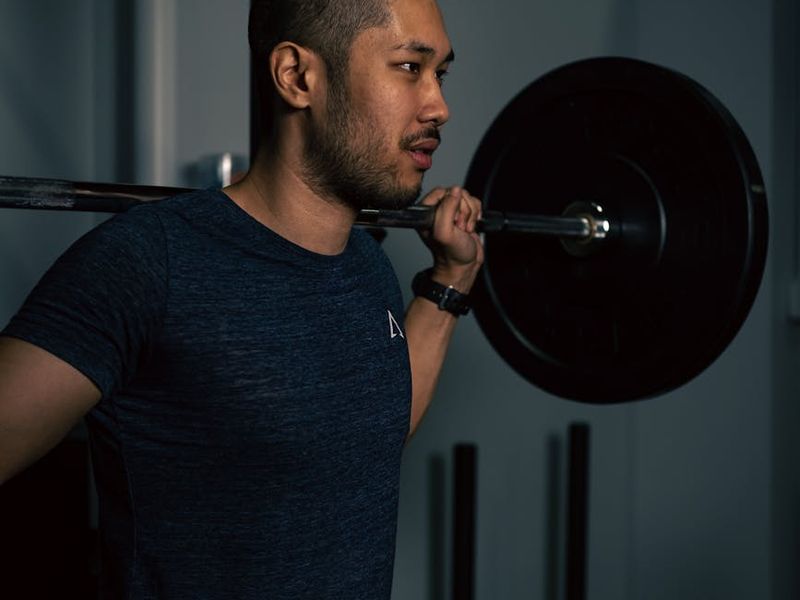 Man lifting dumbbells with focused expression in dark studio