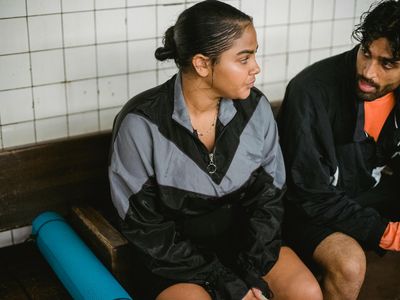 Man sitting on a bench drinking water after workout